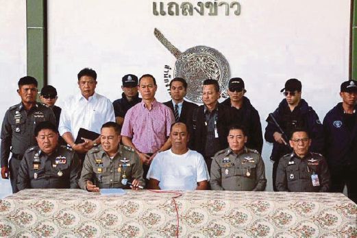 KETUA Polis Somyot Pumpunmuang (duduk, dua dari kiri) memperkenalkan Ko Tong (duduk, tengah) kepada wartawan di Bangkok, semalam.