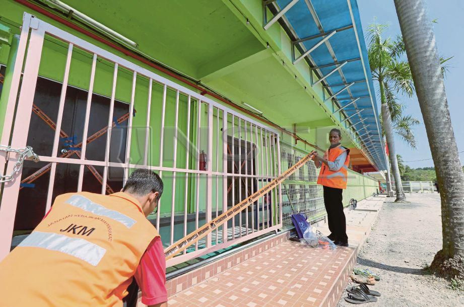 ANGGOTA penguat kuasa Kedah  melekatkan pita pelekat larangan menceroboh pada pintu pagar bangunan. Gambar kecil, pita pelekat turut dilekatkan pada pintu masuk.