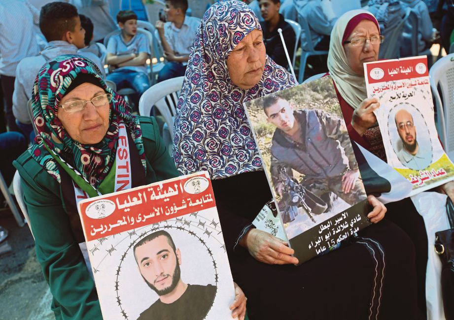 SEKUMPULAN wanita Palestin memegang gambar anggota keluarga mereka yang ditahan di penjara Israel ketika mengadakan tunjuk perasaan di Ramallah, Tebing Barat,  mendesak pembebasan tahanan Palestin dari penjara di Israel.  - EPA 