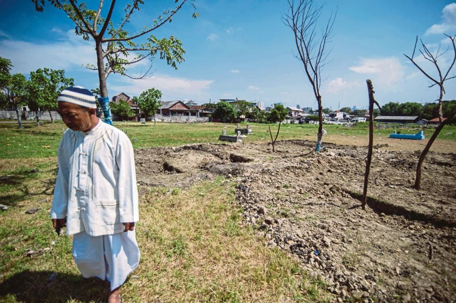 SEORANG lelaki di kawasan tanah perkuburan yang dikambus penduduk tempatan yang enggan membenarkan penyerang nekad dikebumikan di Surabaya. - AFP  