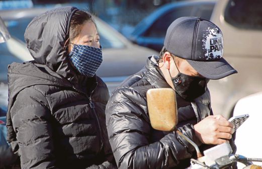 SEPASANG suami isteri menunggang motosikal di jalan raya di Beijing dengan menggunakan topeng mulut, semalam.