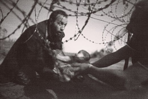 PEMENANG pertama, gambar menunjukkan seorang lelaki menyerahkan seorang bayi di bawah kawat berduri di sempadan Serbia dan Hungary yang dirakam pada 28 Ogos tahun lalu. 