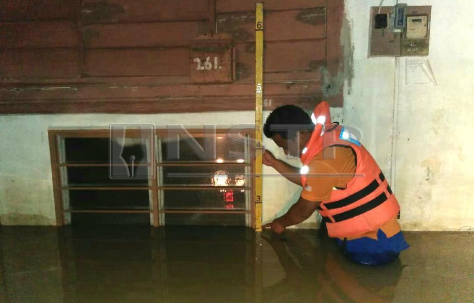 ANGGOTA Angkatan Pertahanan Awam Malaysia (APM) Kota Setar menyukat paras air di rumah penduduk di Kampung Lapangan Terbang di Kepala Batas berikutan hujan lebat sejak petang hari ini. FOTO ihsan APM.