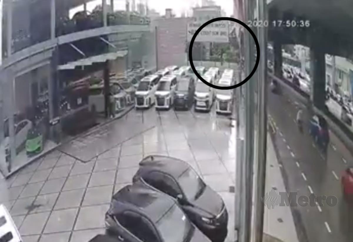 TANGKAP layar dari rakaman kamera litar tertutup menunjukkan mangsa terjatuh dari jejambat, ke pusat jualan kereta terpakai.  
