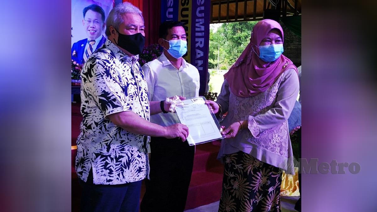 Amar Awang Tengah menyampaikan surat hak milik tanah kepada salah seorang penduduk Kampung Rantau Panjang. FOTO Roji Kawi