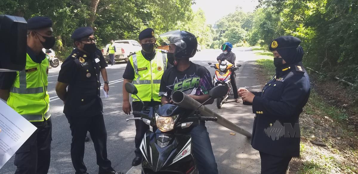 Anggota JPJ sedang memeriksa kenderaan termasuk motosikal yang mahu ke Padang Besar melalui Jalan Kangar-Padang Besar di Tasoh. FOTO AIZAT SHARIF