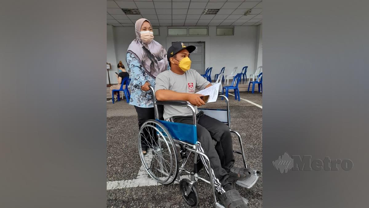 RAJA Nadzrin dibantu Rozaimah keluar dari Kompleks Sukan Masjid Tanah selepas menerima vaksin. FOTO Hassan Omar