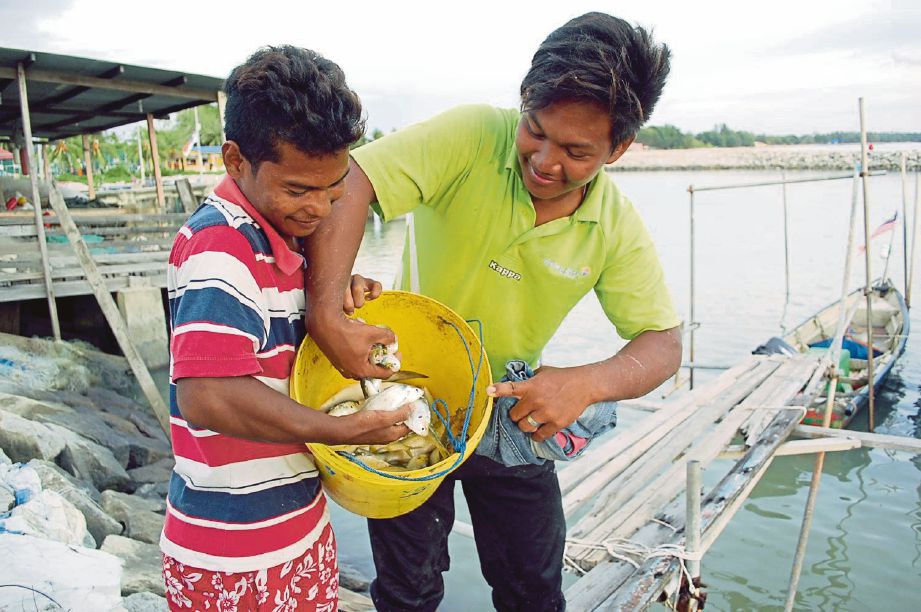 MOHD Nur Afif (kanan) dan Mohd Aidil menunjukkan anak ikan yang  diperoleh.