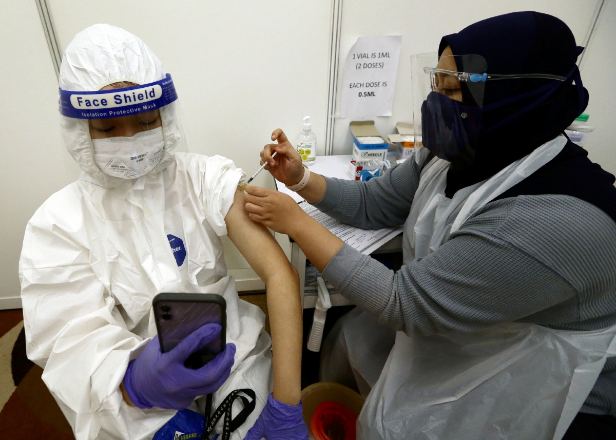 PELAJAR Xiamen University Malaysia (XMUM) memakai set pakaian pelindung diri (PPE) ketika menerima suntikan vaksin di Pusat Pemberian Vaksin (PPV) mega Movenpick Hotel & Convention Centre KLIA (Movenpick), Sepang. FOTO Mohd Fadli Hamzah