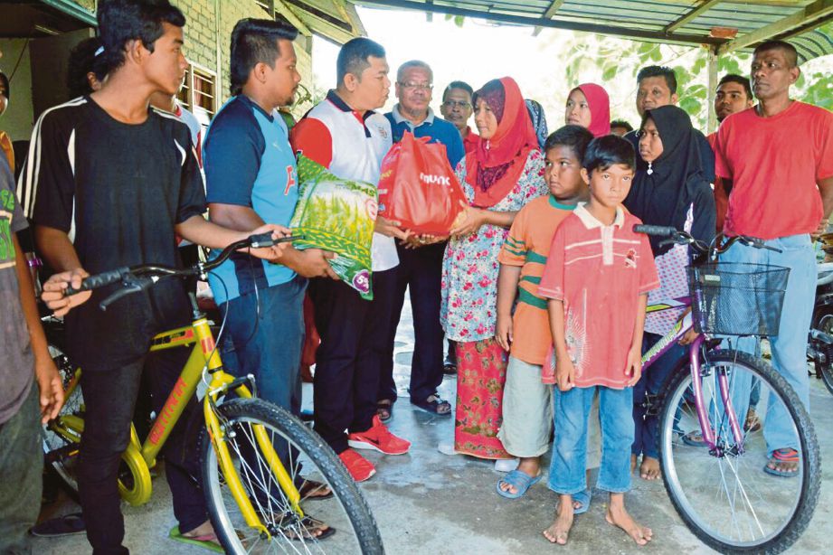 KETUA Pemuda UMNO Nibong Tebal, Mohd Norhiesam Ismail (tiga dari kiri) menyampaikan sumbangan dua basikal dan barang keperluan harian, semalam.  