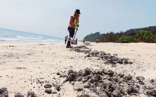PEKERJA Alam Flora Sdn Bhd membersihkan tompokan minyak yang mencemari kawasan pantai.