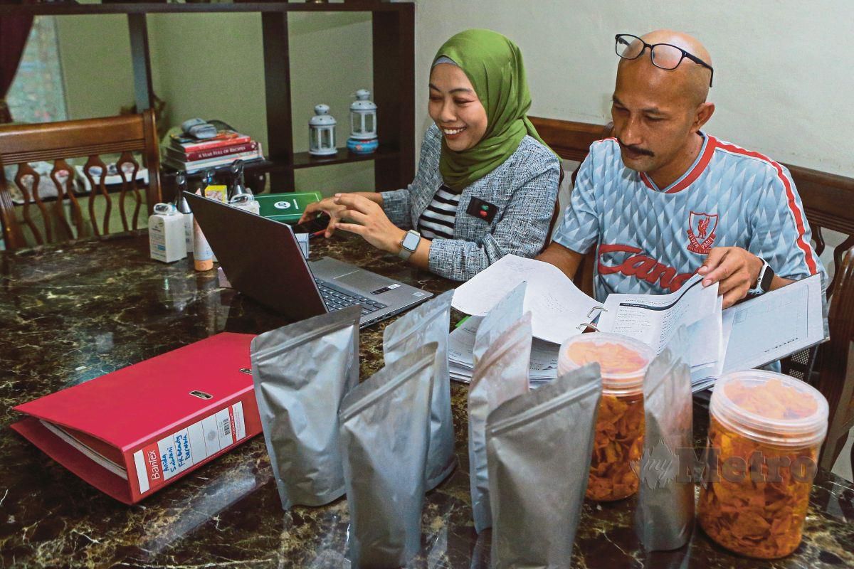 PENIAGA produk makanan, Mohd Azis Ngah bersama isteri beliau, Anida Salwani Abdul Hadi yang berniaga produk kecantikan menguruskan jualan melalui atas talian di kediaman mereka di Alam Budiman, Shah Alam. 