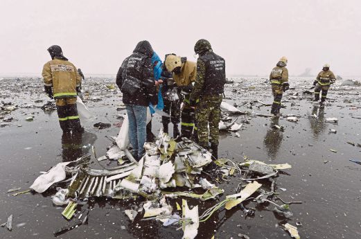 PASUKAN penyelamat memeriksa serpihan pesawat yang berterabur di sepanjang landasan.