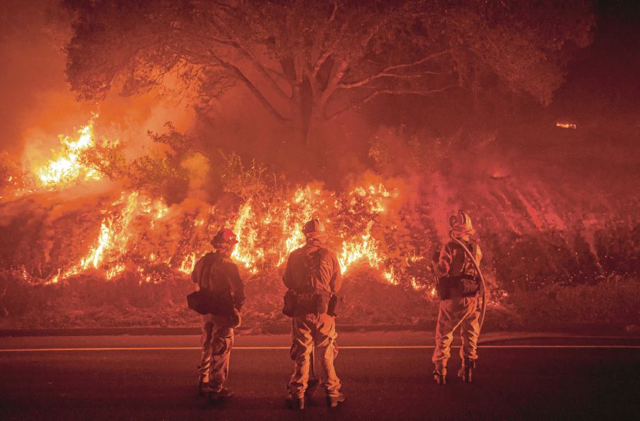 BOMBA mengawasi kebakaran di seberang jalan di Detwiler berhampiran bandar Mariposa, California, semalam. - AFP