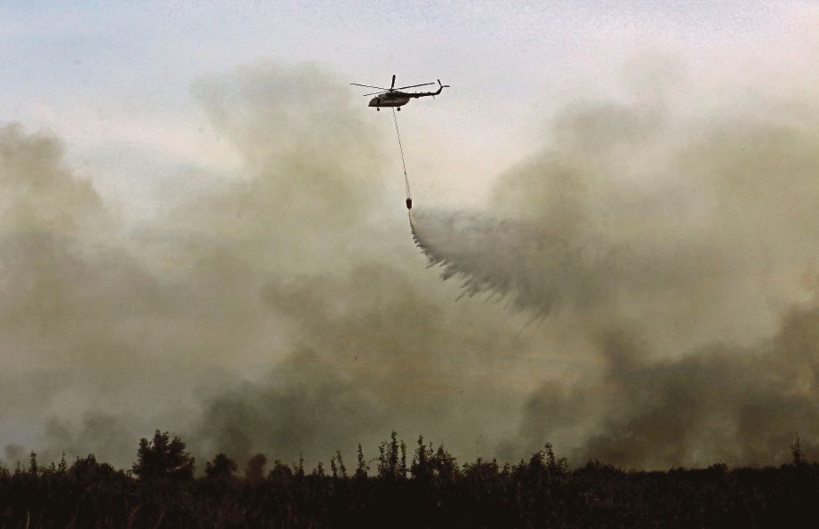 SEBUAH helikopter menggugurkan air di kawasan kebakaran hutan di Ogan Ilir berhampiran Palembang, baru-baru ini. - Antara Foto