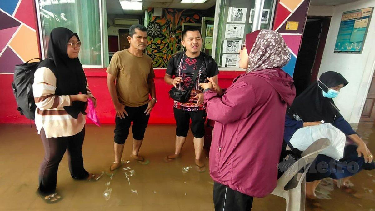 Muhammad Fadhli (dua dari kanan) dan isterinya mendapatkan bantuan bomba selepas terperangkap selama tiga hari di Rantau Panjang akibat banjir. FOTO Syaherah Mustafa.