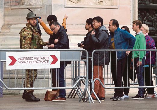 TENTERA Itali memeriksa pelancong yang beratur untuk memasuki gereja Duomo di Milan, semalam.