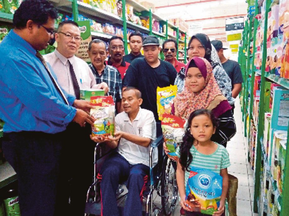 MAS Imran (kiri) menyampaikan sumbangan barangan keperluan kepada keluarga Azmi di Pasaraya Econsave, Taman Daya, Johor Bahru. 