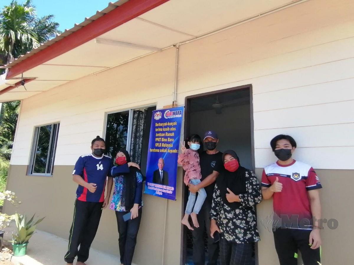 MASRI (tiga dari kanan) bersama keluarganya di hadapan  rumah PPRT yang  diterima mereka di Kampung Tanjung Batu, Kota Marudu, baru-baru ini.