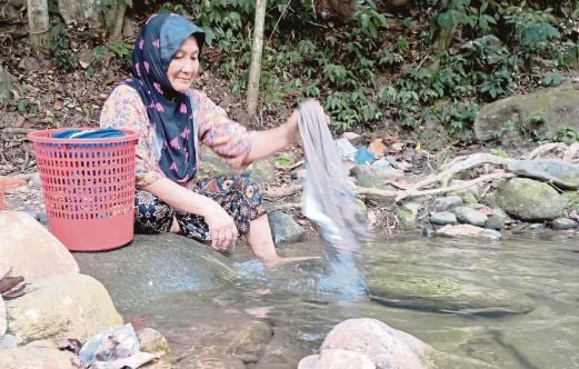 ARBAAYAH dari Kampung Bendang Dalam, Merbok, membasuh pakaian di sungai dekat Lembah Bujang, semalam.
