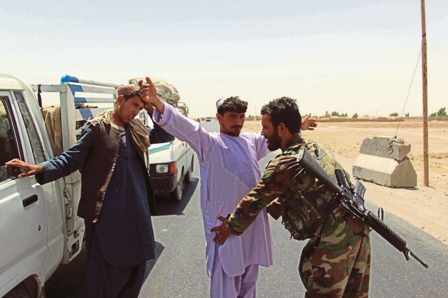 TENTERA Afghanistan memeriksa orang ramai di sebuah pos kawalan di lebuh raya menuju ke Kandahar, di mana 43 askar terbunuh, semalam. - EPA  