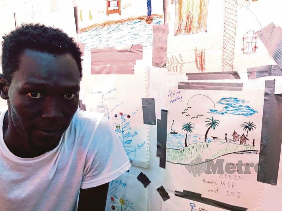 EZZO bergambar di sisi lukisannya memaparkan perkampungannya di selatan Sudan. - AFP 