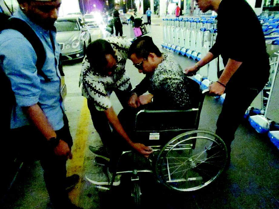 FIRMAN yang berkerusi roda dibantu untuk menaiki kenderaan.