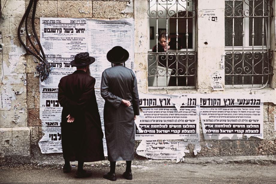 DUA lelaki Haredi melihat maklumat yang ditampalkan di satu dinding.