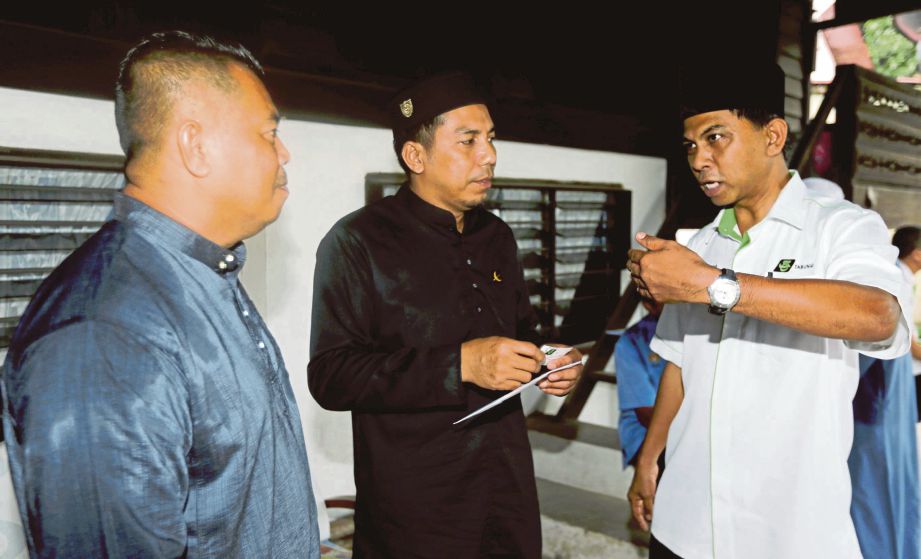 ABU Shukor  (kanan) berkata sesuatu kepada anak sulung  Siti Aishah,  Abdul Halim Zakaria (kiri) selepas menyerahkan sumbangan, semalam.