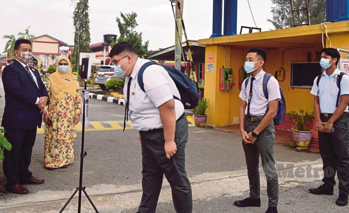 PENGARAH Pendidikan Negeri Terengganu, Salim Ab Ghani bersama Pengetua Sekolah Kebangsaan Dato Razali Ismail, Sabariah Abd Mubin melihat pelajar tingkatan lima melakukan saringan suhu badan sebelum memasuki pekarangan sekolah bagi memulakan sesi persekolahan secara bersemuka, semalam.
