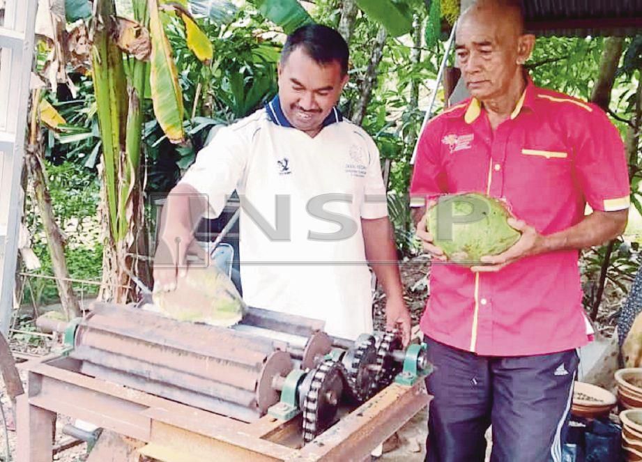 SUHANI  (kiri) dan abang iparnya Omar Man   menunjukkan cara menggunakan mesin mengupas kelapa yang dicipta sendiri.