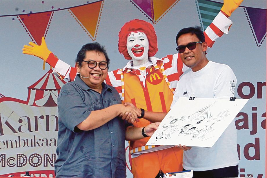 LAT (kiri) menyampaikan lukisan karikatur kepada Azmir pada pelancaran Burger Syok di Putrajaya. 