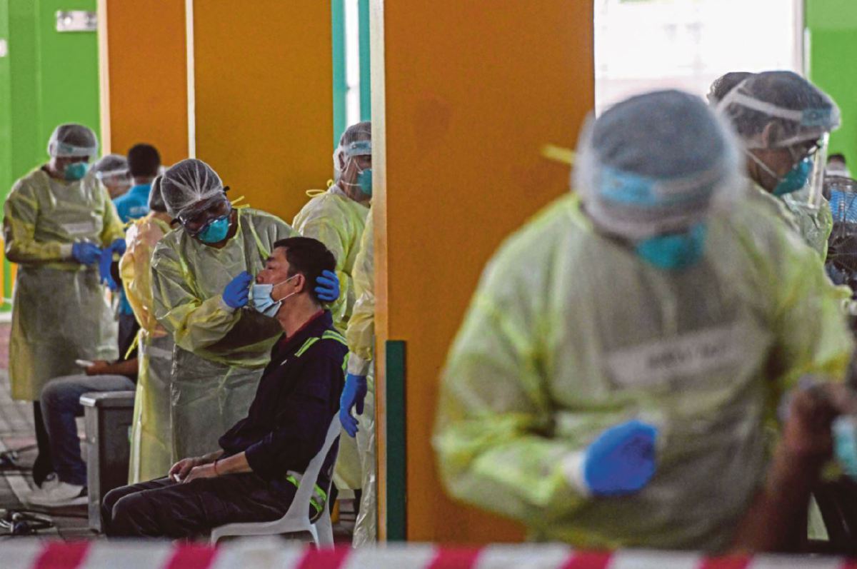 Gambar fail, petugas kesihatan Singapura melakukan ujian saringan Covid-19 ke atas pekerja yang kembali bertugas di negara itu. FOTO AFP.