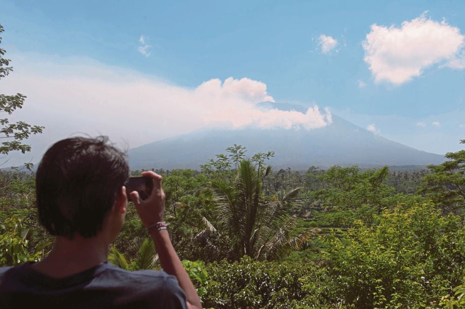SEORANG penduduk merakam gambar Gunung Agung dari stesen pemantau di Kampung Rendang di Karangasem, Bali kelmarin. - Reuters