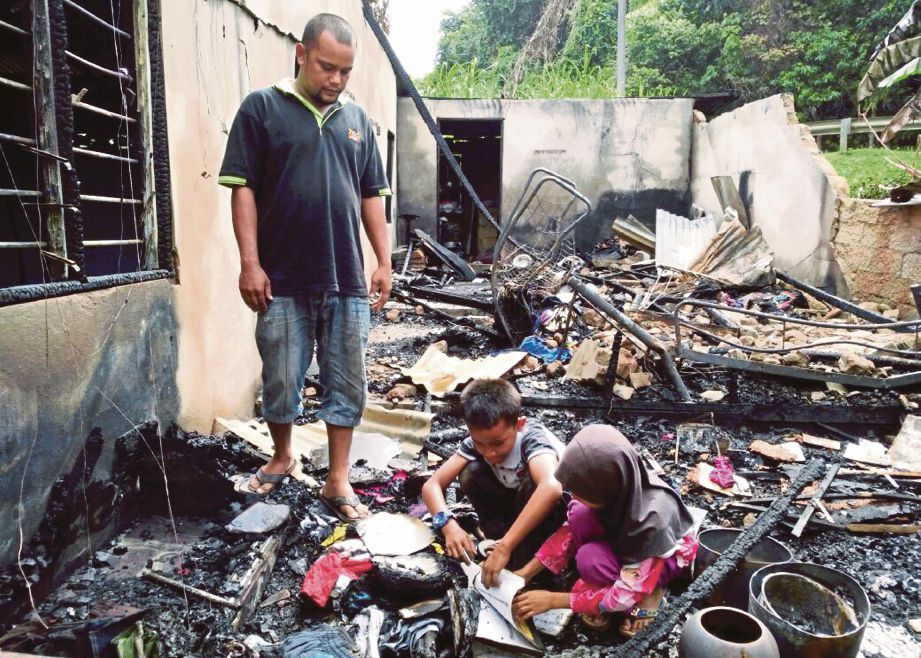 DUA anak Mohd Nawawi melihat  buku sekolah mereka yang   hangus dalam kebakaran.