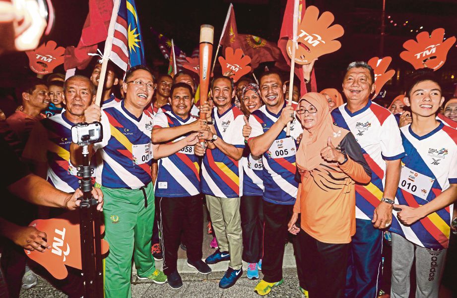 AMINUDDIN (tengah)  membawa obor Kuala Lumpur 2017 untuk diserahkan kepada Ahmad Bashah. 