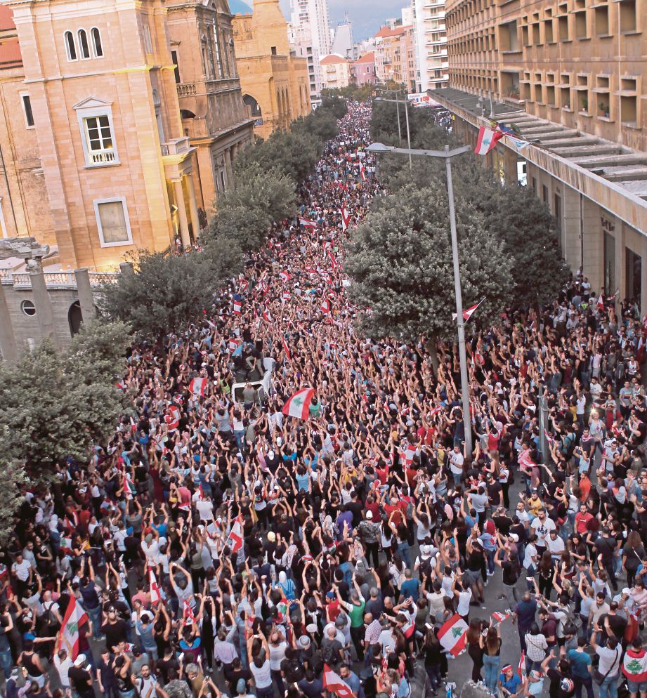 PENUNJUK perasaan mengibarkan bendera Lubnan sambil menjerit slogan anti-kerajaan ketika demonstrasi. FOTO EPA