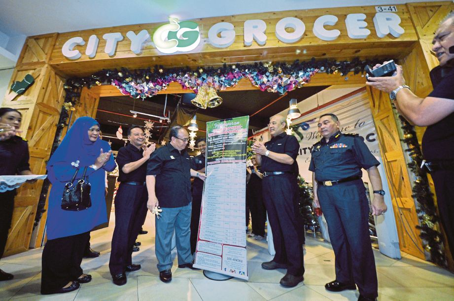 Henry (tiga dari kiri) melancarkan gimik perasmian Pelaksanaan Skim Kawalan Harga Musim Perayaan Krismas 2016 di sebuah pasar raya di Kota Kinabalu. 