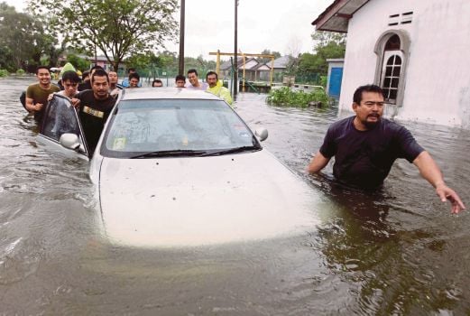 PENDUDUK membantu menolak kereta yang ditenggelami air di Taman Murni Permai, Tok Jembal.