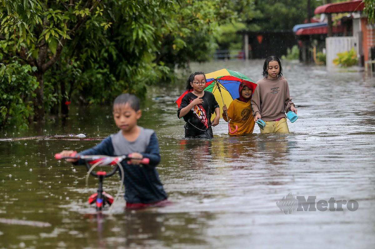 KANAK-KANAK meredah banjir  selepas kediaman mereka di Taman Murni Permai, Tok Jembal, Kuala Nerus dinaiki air. FOTO Ghazali Kori.