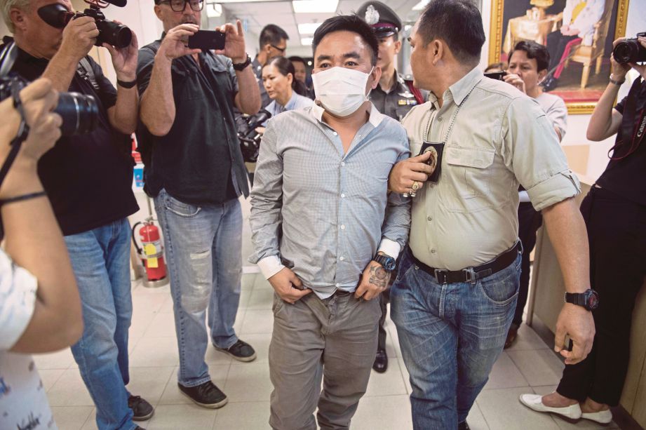 BOONCHAI dibawa  anggota polis di sebuah balai polis di Bangkok untuk  ditahan reman kerana disyaki menyeludup haiwan liar. - AP