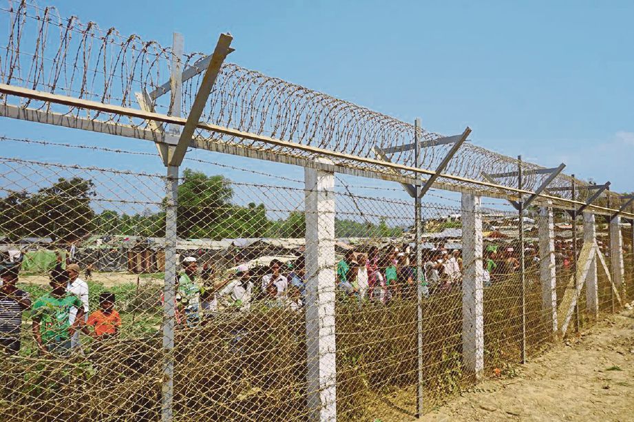 PELARIAN Rohingya berkumpul di sebalik pagar sempadan Myanmar dekat Tombru, Bangladesh. - AFP