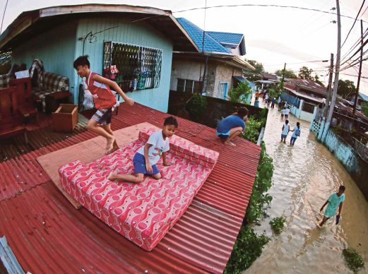 BEBERAPA penduduk berlindung di bumbung rumah di kampung Calumpit di wilayah Bulacan, utara Filipina, semalam selepas kampung itu dinaiki air berikutan hujan lebat yang dibawa taufan Koppu. 