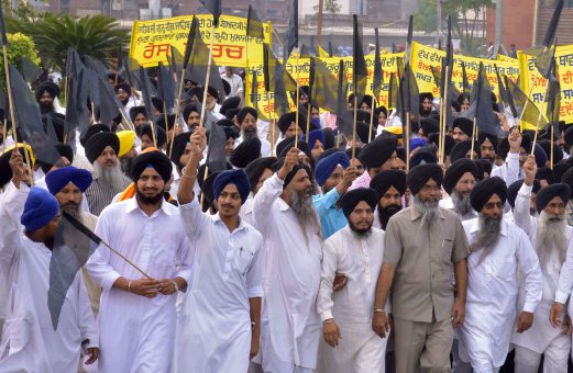AKTIVIS sebuah persatuan Sikh berarak dengan membawa bendera hitam ketika mengadakan tunjuk perasaan membantah pencemaran kitab suci mereka, di Amrtisar, Punjab, semalam.  