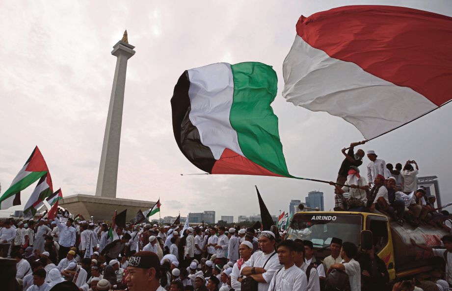 AKTIVIS mengibarkan bendera Indonesia dan Palestin dalam satu tunjuk perasaan membantah Trump di Jakarta baru-baru ini. - EPA