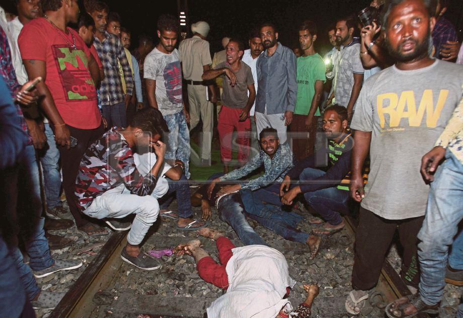 ORANG ramai melihat mayat mangsa yang terbaring di atas landasan selepas dirempuh kereta api di Amritsar, India kelmarin. - Reuters