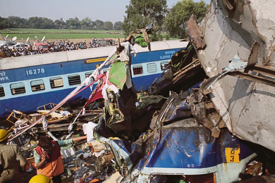 ANGGOTA penyelamat mengeluarkan mayat dari bangkai kereta api. - Reuters  