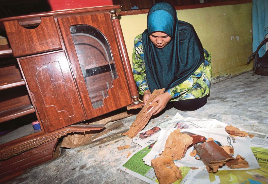 NORRITA Husin mengasingkan serpihan almari yang rosak akibat banjir di Kampung Tok Muda, Kapar.
