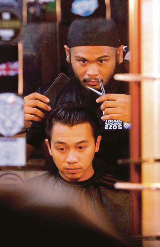 MUHAMMAD Syafiq menunjukkan gaya memotong rambut untuk pelanggannya.