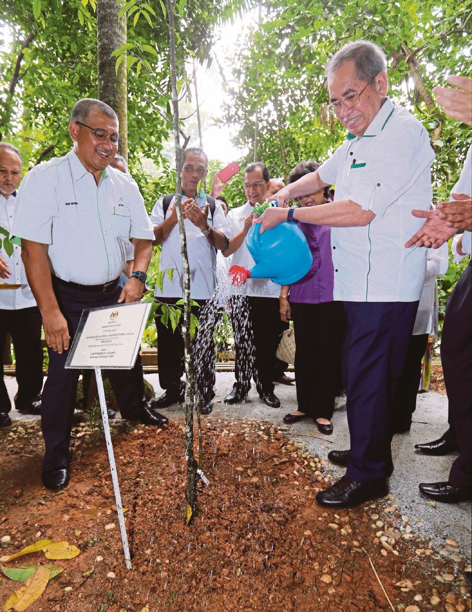WAN Junaidi  (kanan) menyiram pokok yang ditanam ketika majlis perasmian Galeri Interaktif NRE di Taman Eko Rimba, Bukit Nanas, semalam.